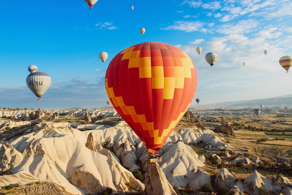 Colorful hot air balloons fly and float over a desert landscape. Original public domain image from Wikimedia Commons