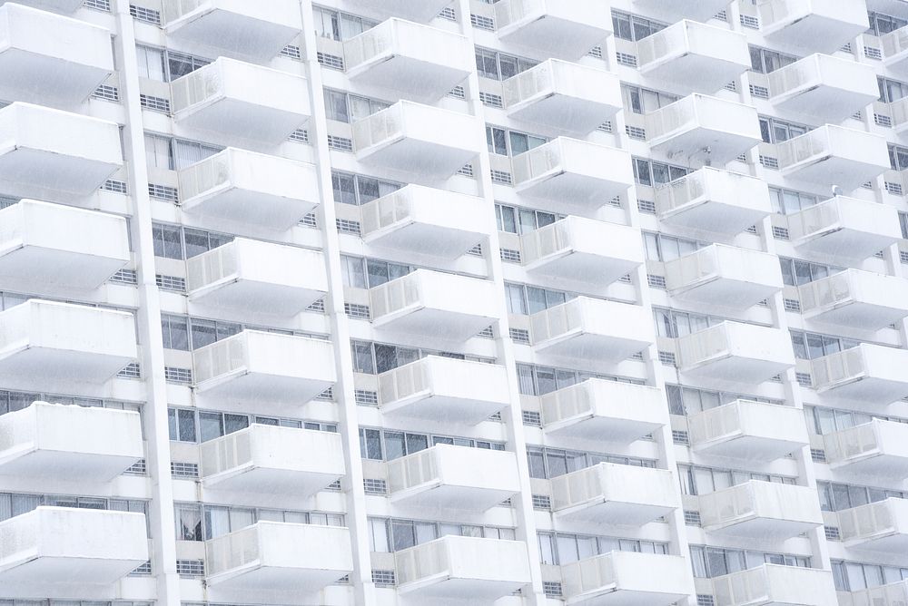 A stern white building facade with identical balconies. Original public domain image from Wikimedia Commons