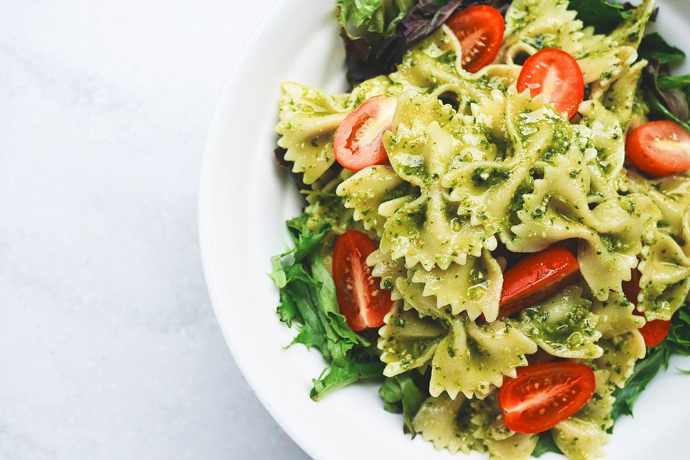 A plate of bow tie pasta, cherry tomatoes, lettuce, and pesto sauce. Original public domain image from Wikimedia Commons