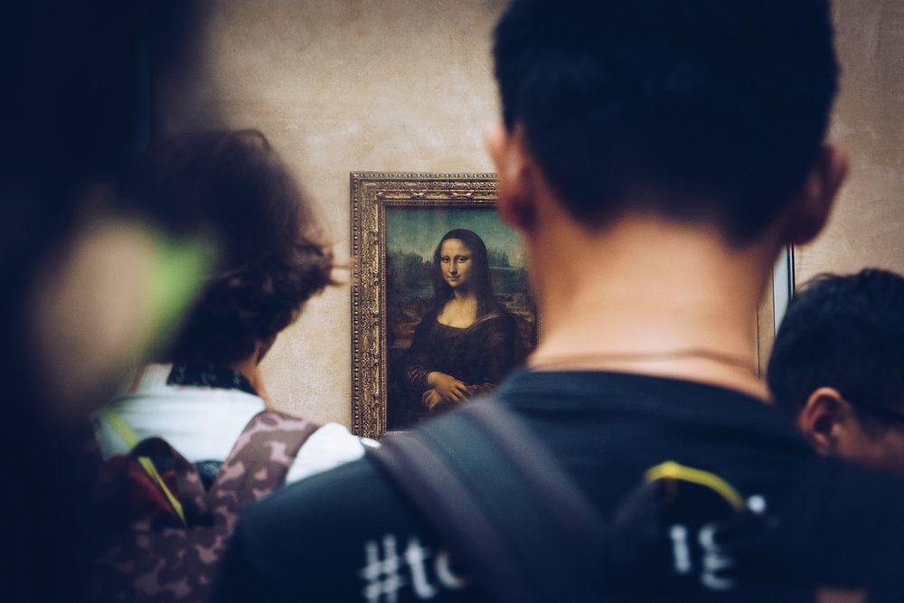 Picture from behind of people viewing the Mona Lisa in Louvre art gallery in Paris. Original public domain image from…