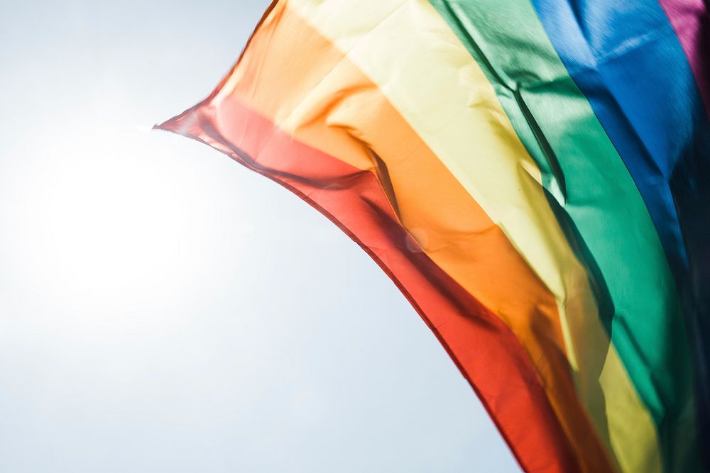 Rainbow pride flag flying in the daytime breeze. Original public domain image from Wikimedia Commons