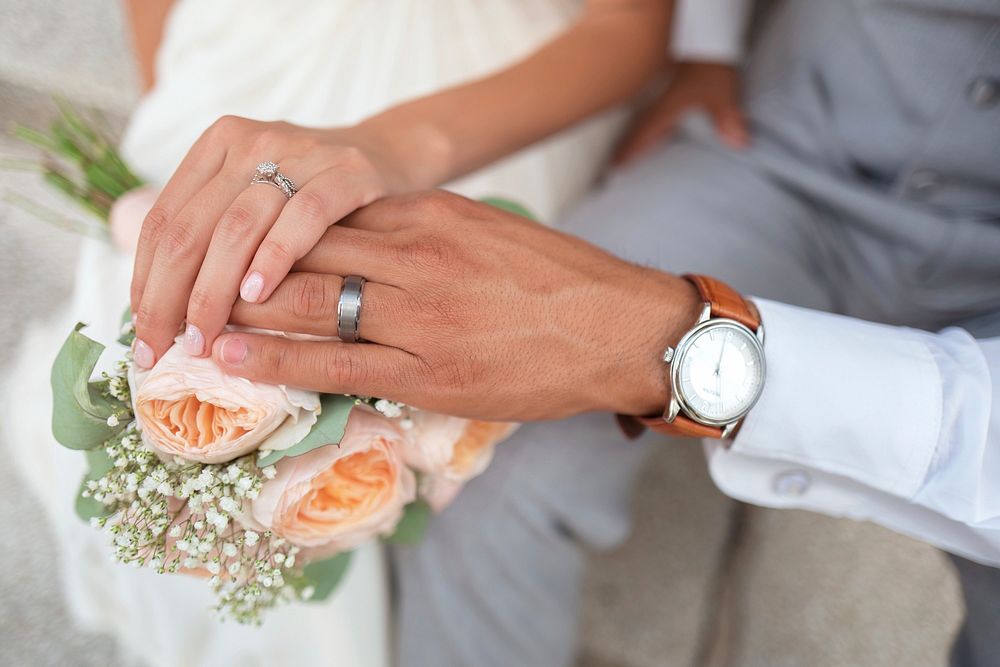Bride and groom's hands touching over wedding bouquet. Original public domain image from Wikimedia Commons