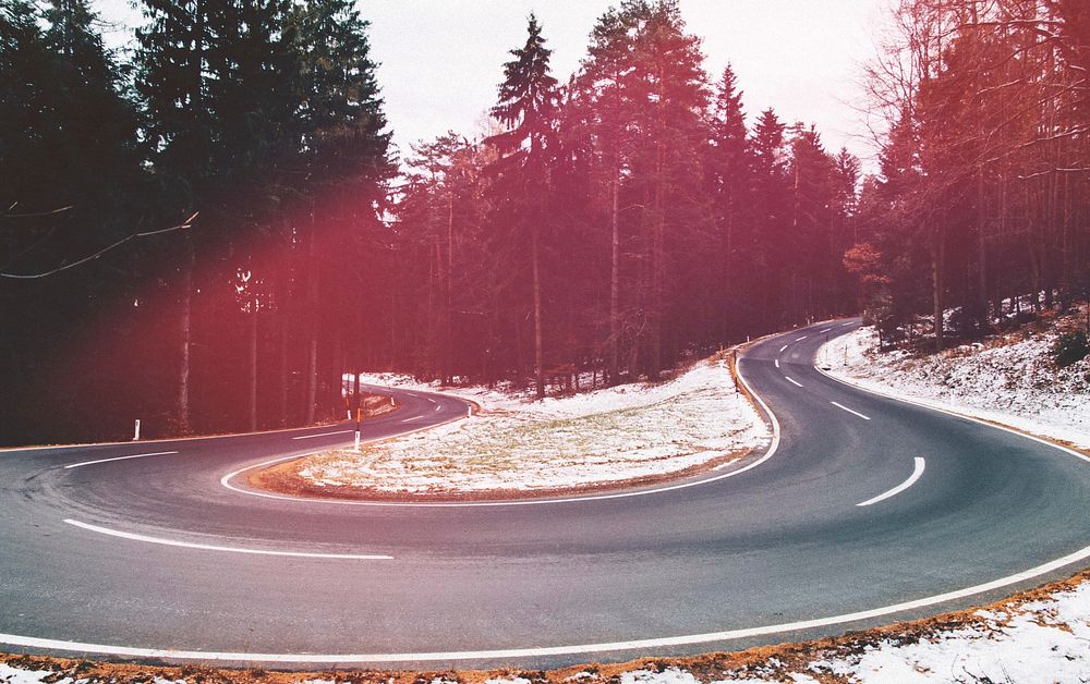 Red tint over a shot of a curve in a tree-lined road. Original public domain image from Wikimedia Commons