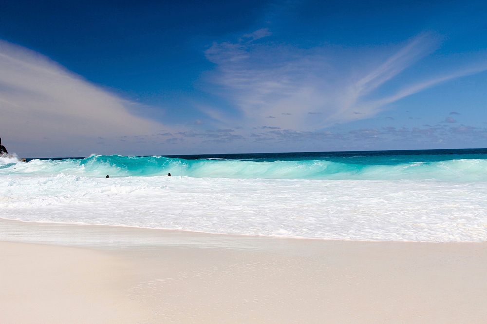 Blue ocean waves splashing on a tropical sand beach at Seychelles. Original public domain image from Wikimedia Commons