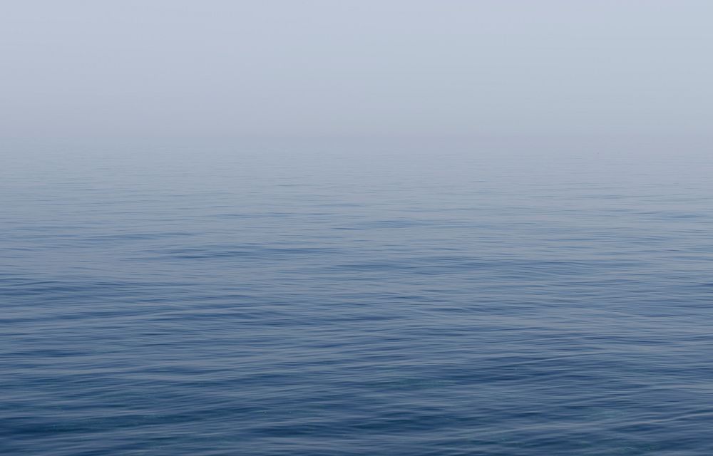 Calm, blue sea covered in a soft mist. Original public domain image from Wikimedia Commons