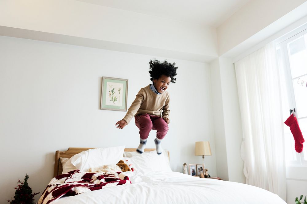 Young kid having a fun time jumping on a bed