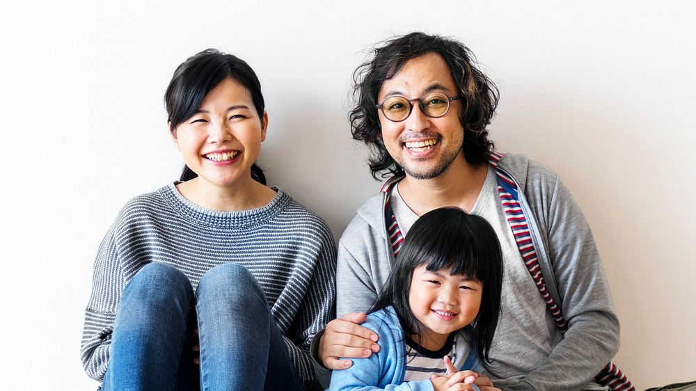 Smiling Japanese family with a daughter sitting on the floor