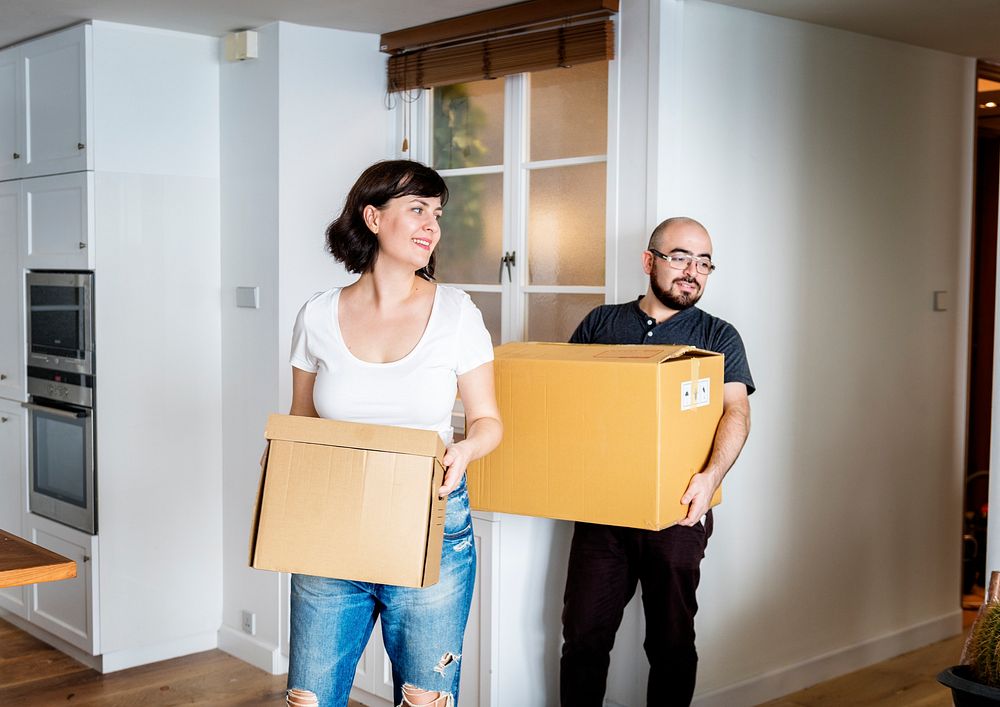 Happy couple moving in together and carrying boxes