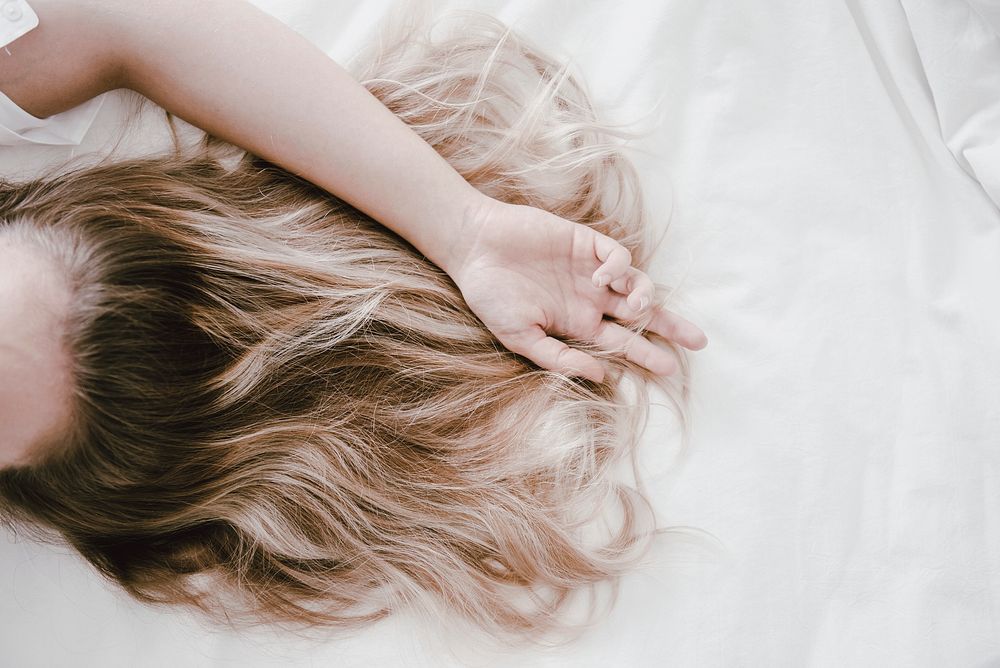 Blonde woman lying on bed, aesthetic photo with design space