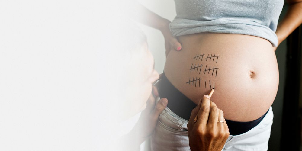 Father marking pregnancy due date on a woman&rsquo;s baby bump text space