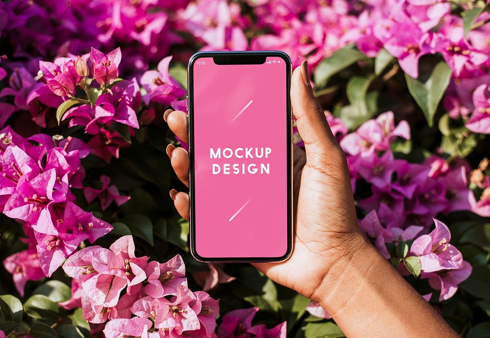 Woman holding a mockup phone over a pink bougainvillea