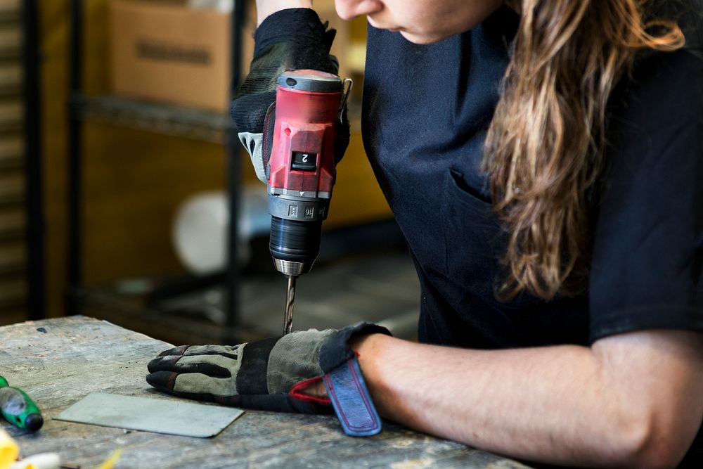 Female mechanic drilling into metal