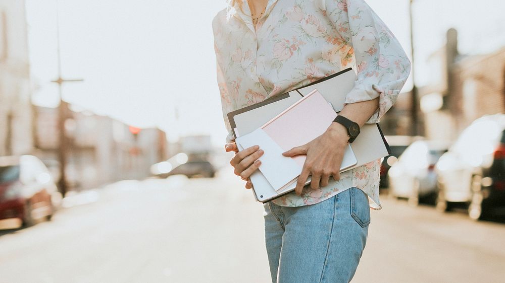 White woman with file folders crossing a street