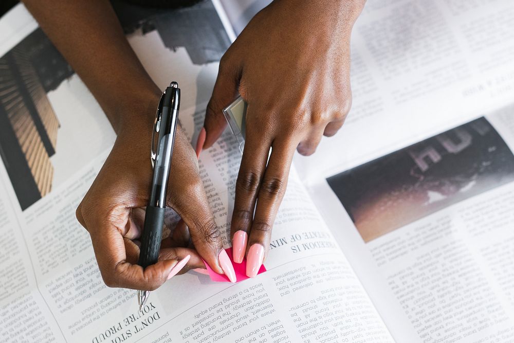 Black woman highlighting an article on the newspaper