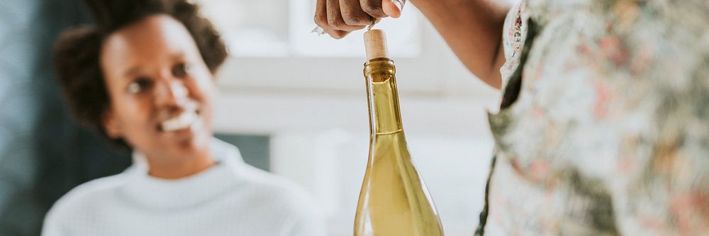Happy black man uncorking a wine bottle
