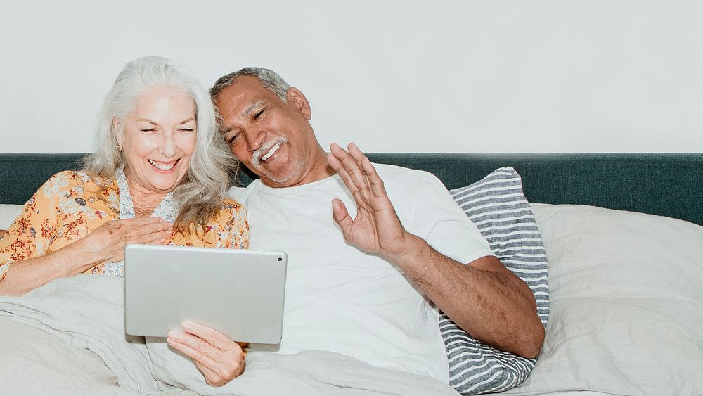 Elderly couple having a video call in bed