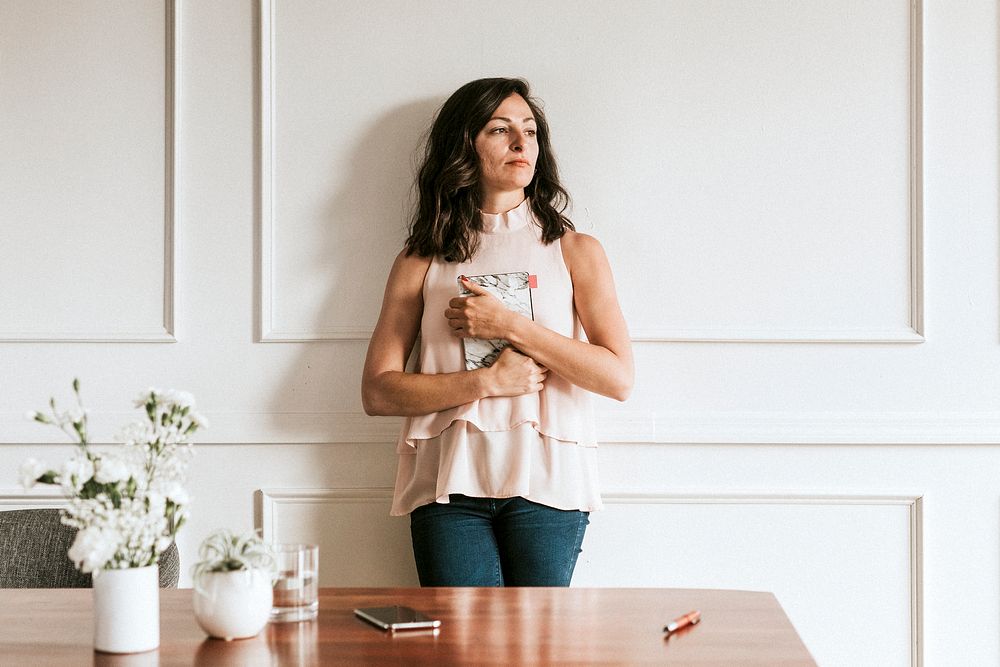 Businesswoman holding a marble textured book standing against the wall