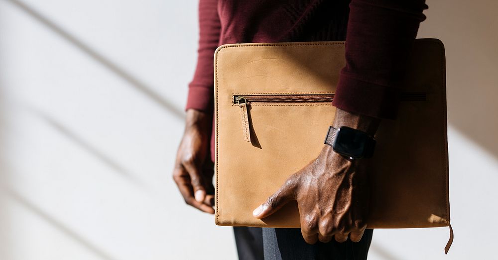Man with a wristwatch holding a brown briefcase