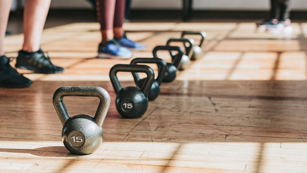 People standing by kettlebells in the gym