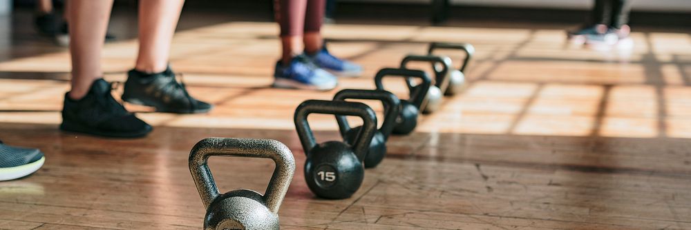 People standing by kettlebells in the gym