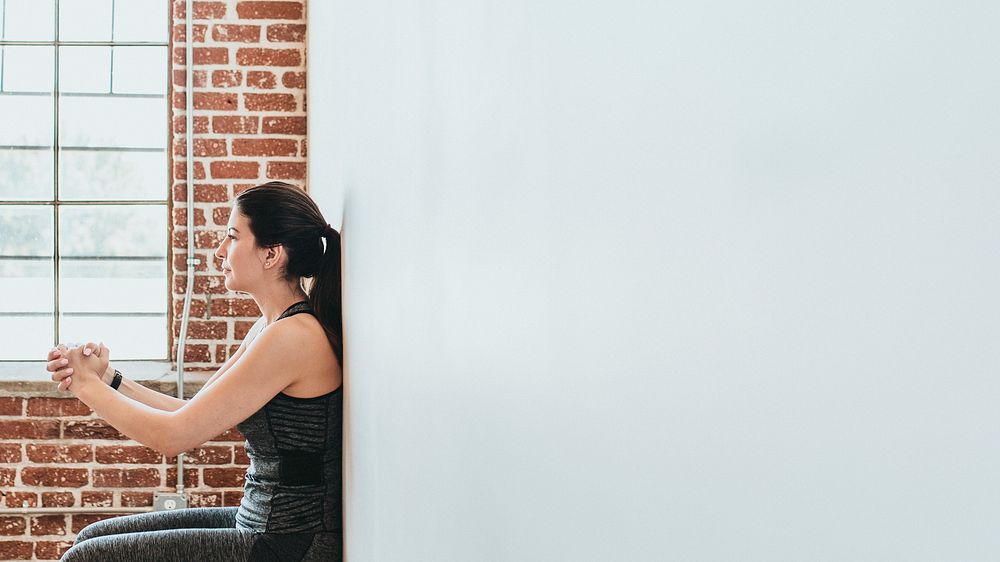 Sporty woman doing squats against a wall