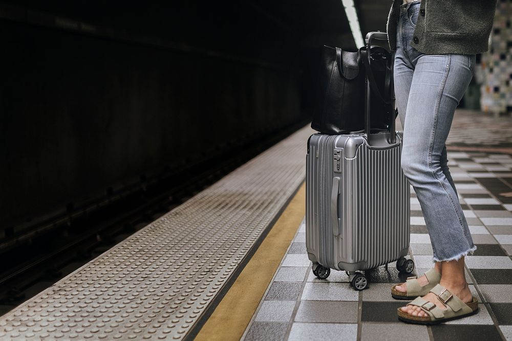 Woman with a suitcase waiting for the train during the coronavirus pandemic