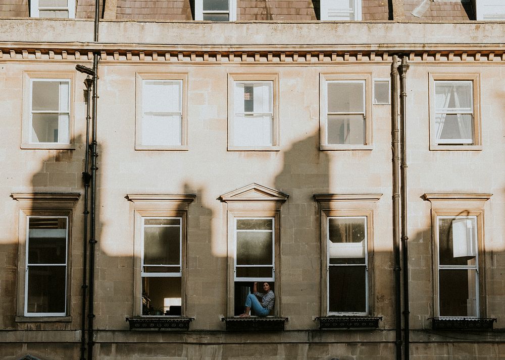 Woman in the window of her apartment during self quarantine due to the covid-19 pandemic in Britain. APRIL 4, 2020 - BATH, UK