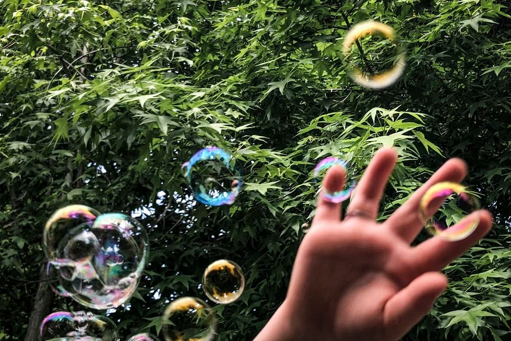 Soap bubbles in the park with kid&rsquo;s hand closeup