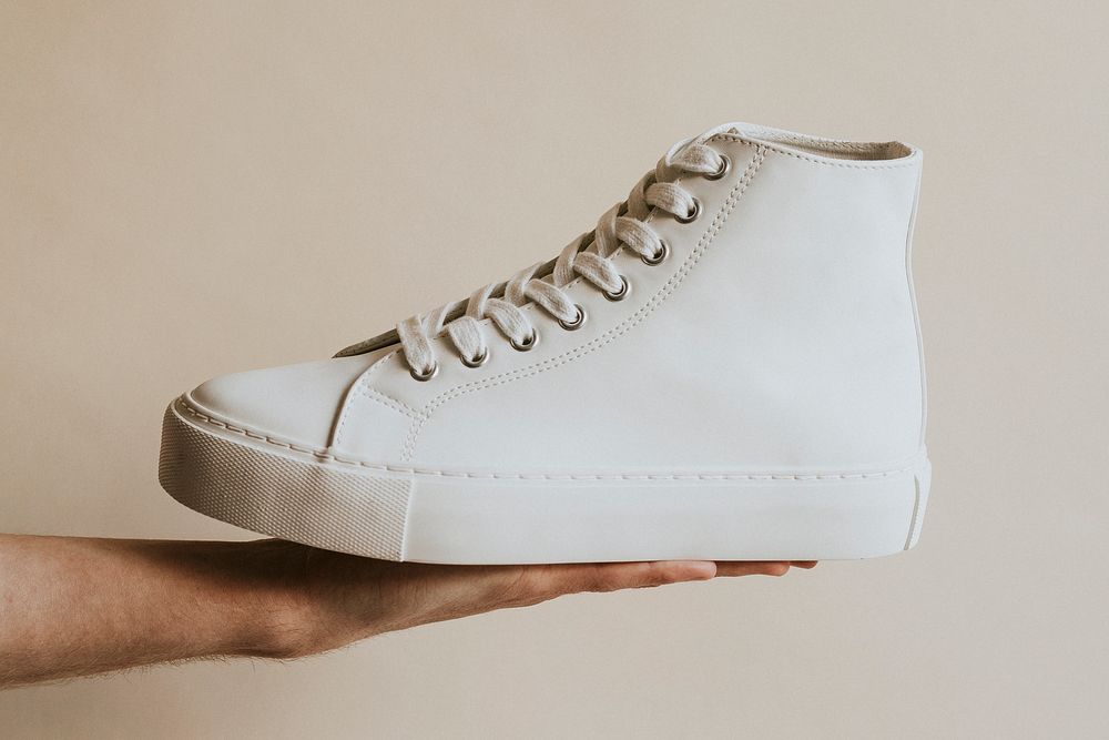 Hand holding white high top sneakers