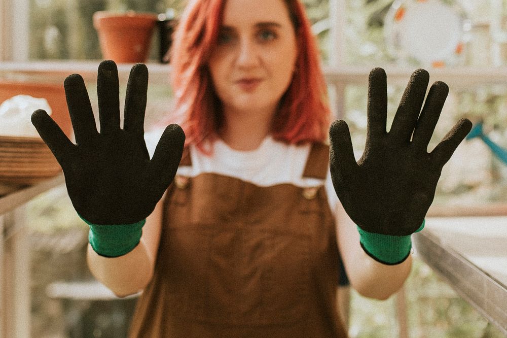 Young woman gardener with black gloves in small organic farm