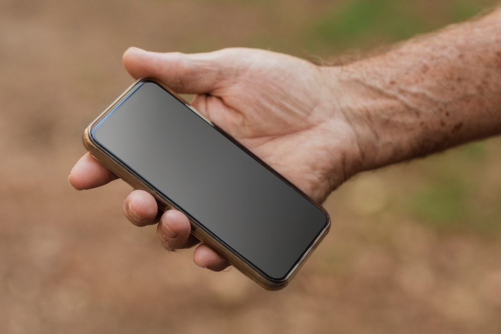 Senior man holding smartphone with black screen