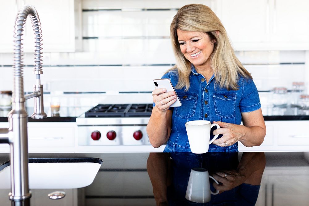 Woman using a mobile phone in the kitchen