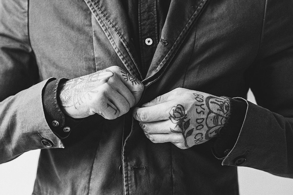 Man with tattooed hands buttoning his jacket. 2 OCTOBER 2020 - CHIPPENHAM, UK