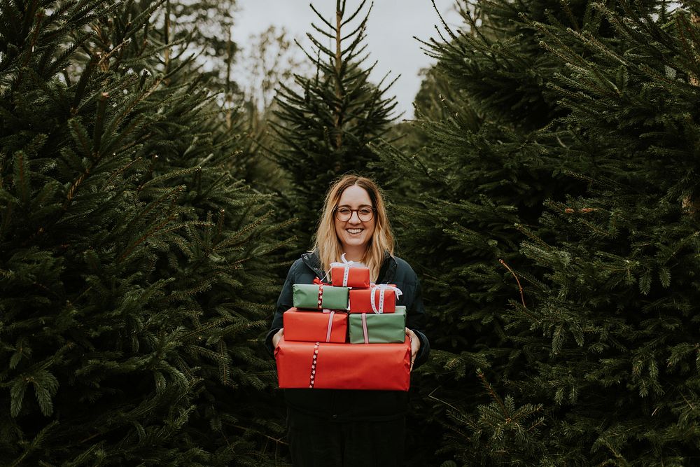 Smiling woman carrying many boxes of Christmas gifts