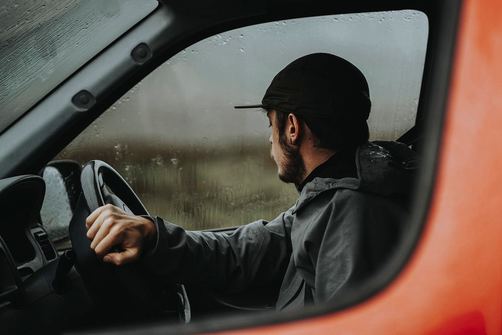 Man driving a red van while raining