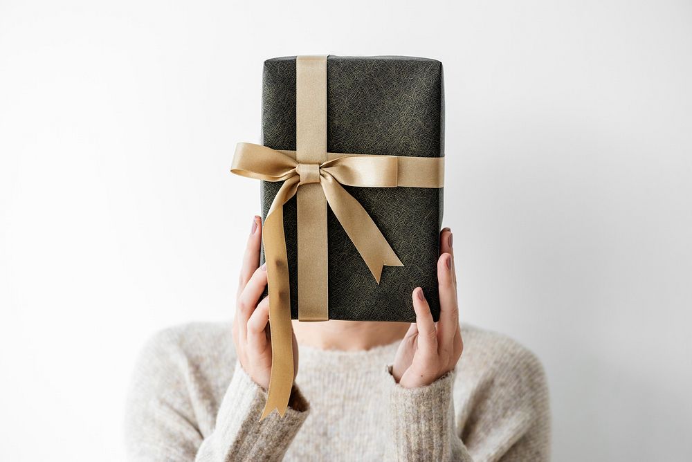 Woman covering her face with a gray present