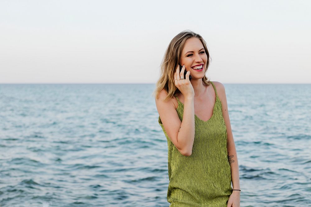 Woman in a green dress talking on her phone at the beach