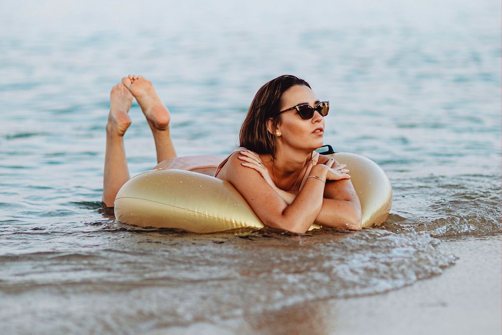 Girl lying on a gold swim tube at the beach