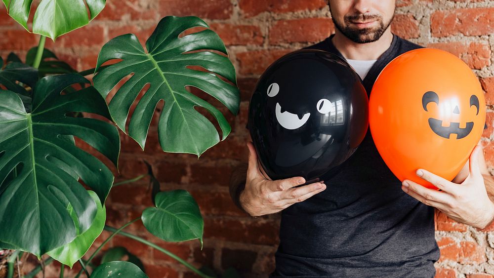 Man with Halloween balloons next to Monstera