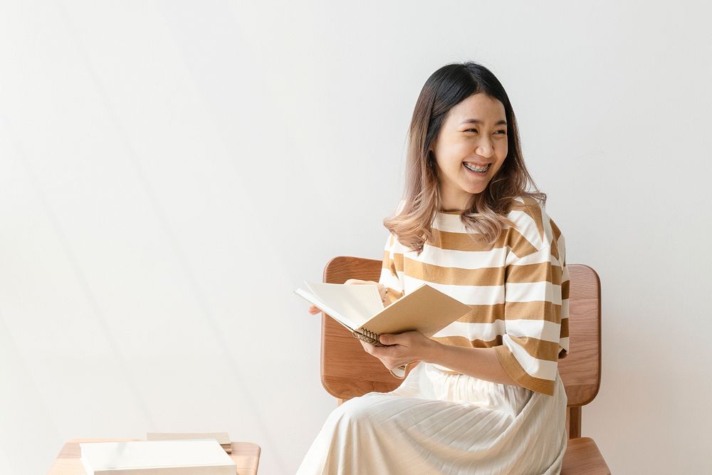 Cheerful Aisian woman reading a book at home