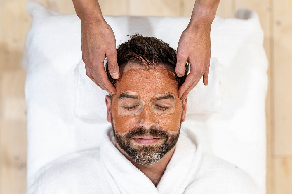 Man relaxing in facial mask spa, self-care photo