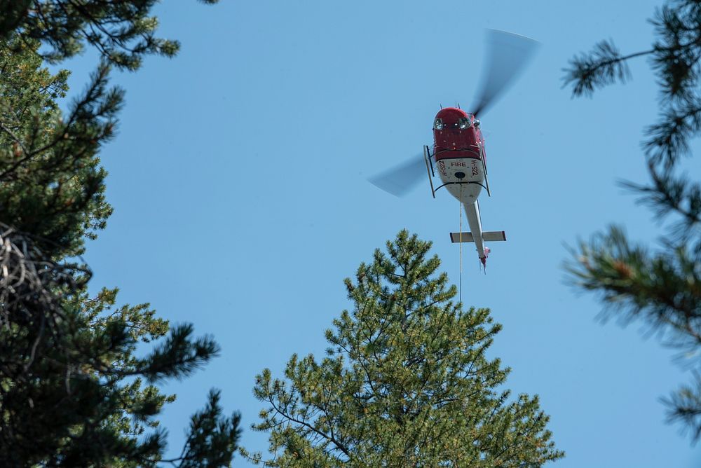 A Bell 212 helicopter drops buckets of water during aerial operations during the Donnell Fire, Stanislaus National Forest…