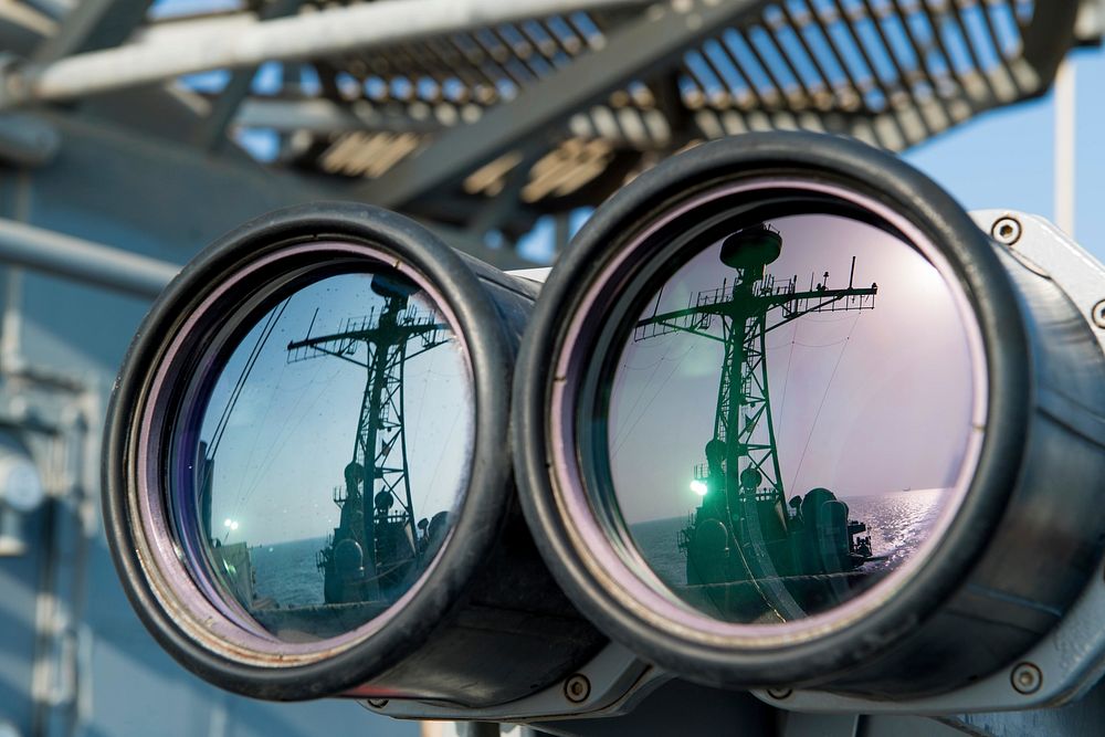 "Big eyes" binoculars are used to scan the horizon as the guided-missile cruiser USS Princeton (CG 59) transits the Strait…
