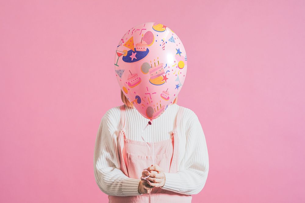 Woman holding festive balloon on plain pink background