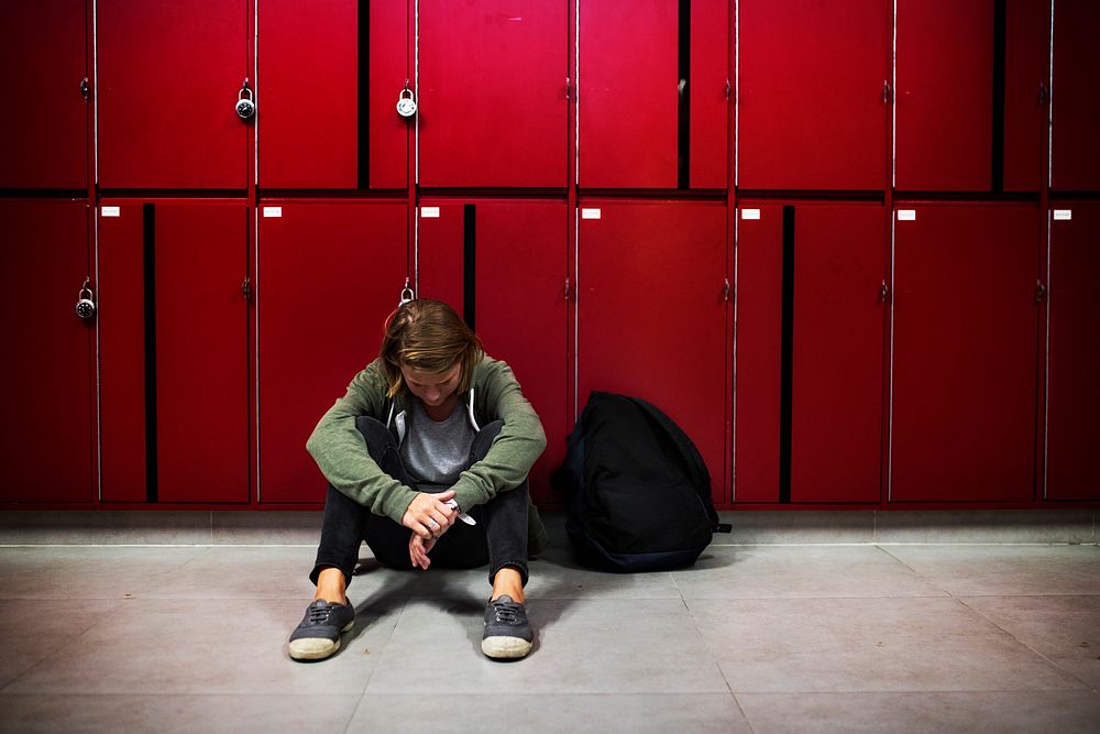 Student bowing his head and sitting on the floor