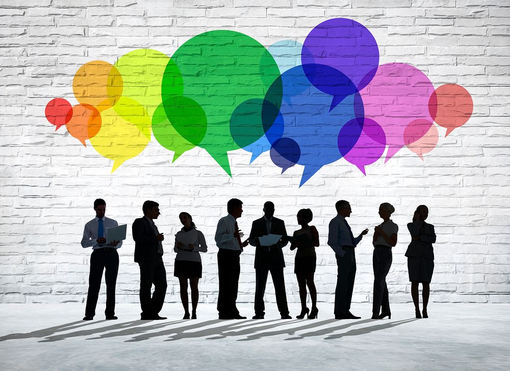Group of business people discussing with colorful speech bubbles above them.