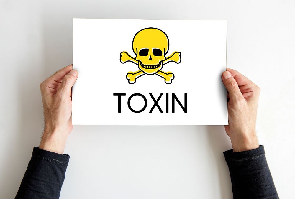 Hands holding placard skull icon and toxin dangerous word