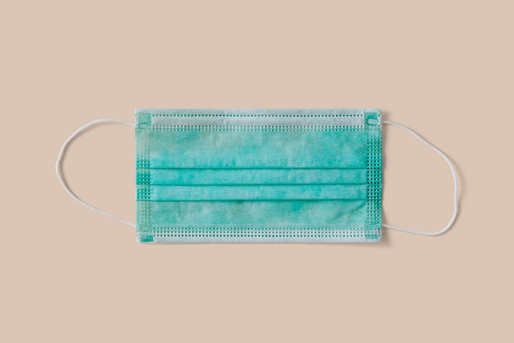 Green surgical mask on a beige background