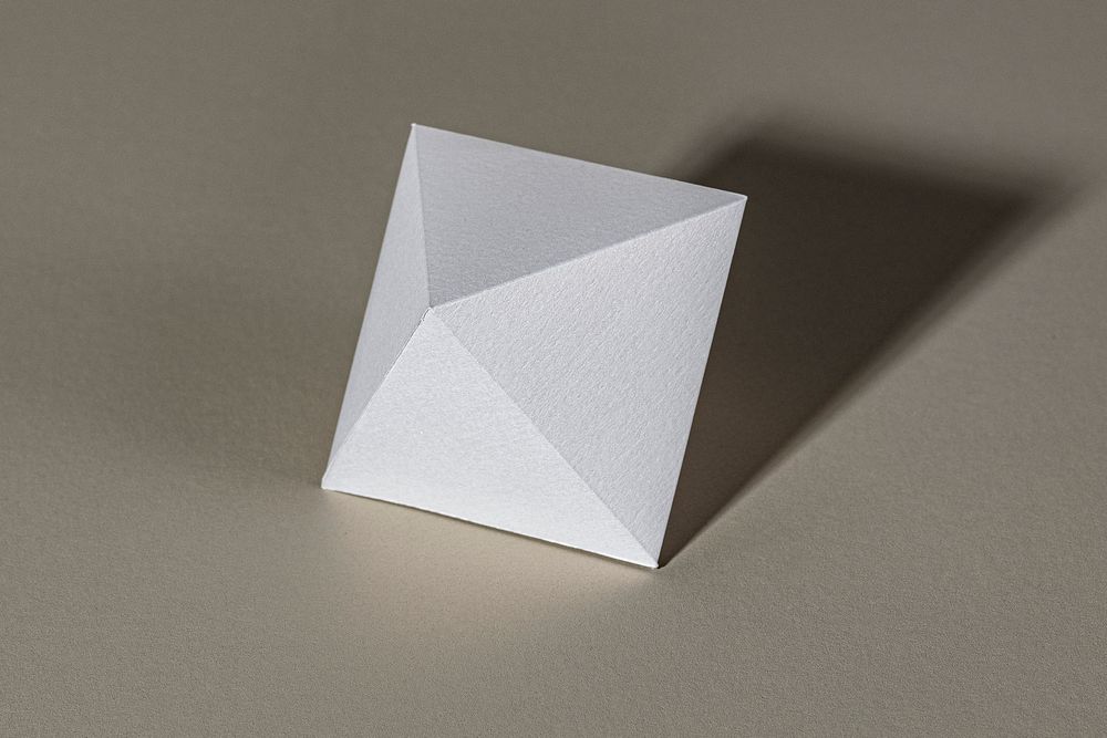 3D silver pyramid paper craft on a beige background