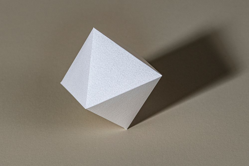 3D silver pyramid paper craft on a beige background